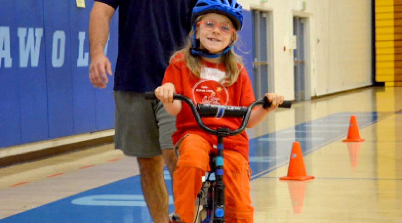 child on bike with instructor following