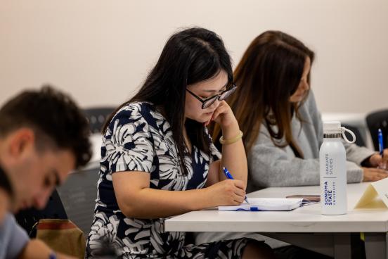 Student seated at desk, taking notes