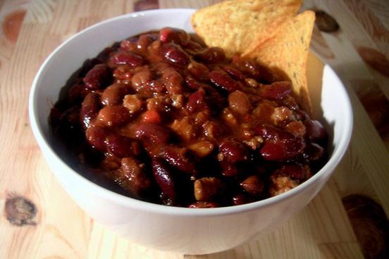 a bowl of chili with two tortilla chips to the side.
