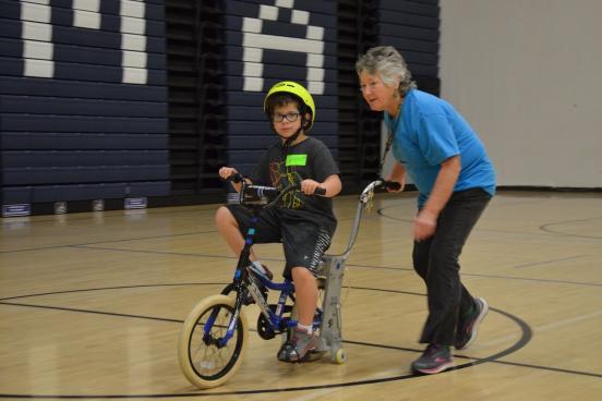 elaine mchugh helping a child ride a bike