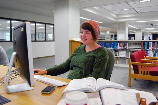 Student using computer and books in library