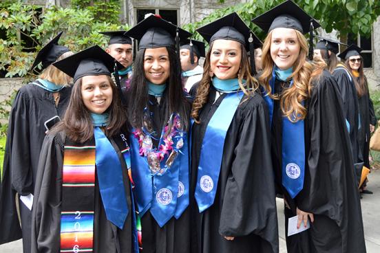 four students in regalia at commencement