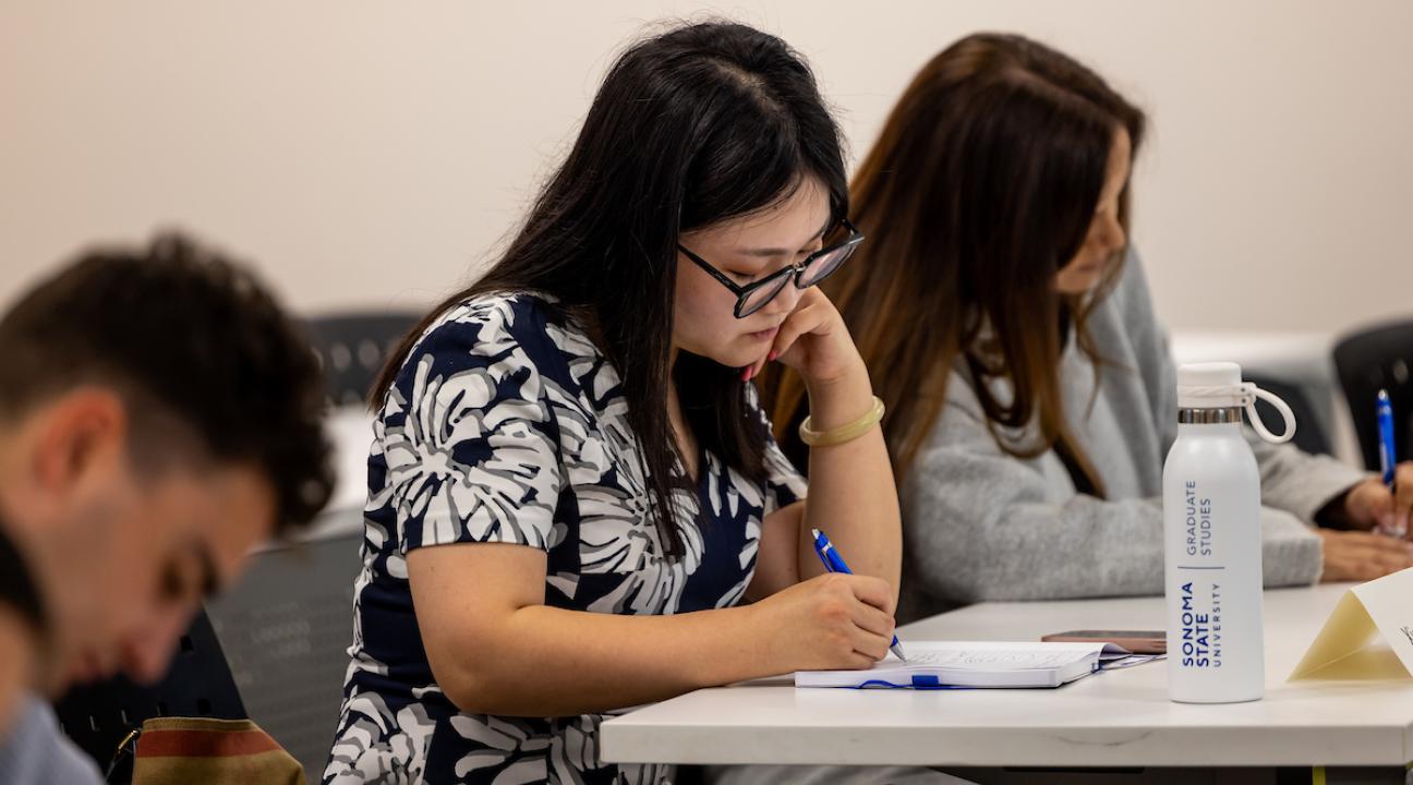 Student seated at desk, taking notes