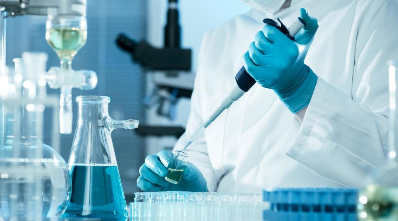 chemist injecting blue liquid into container