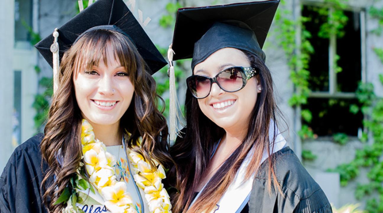 two students pose for a picture with their cap and gown