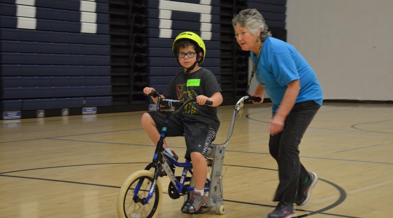 elaine mchugh helping a child ride a bike
