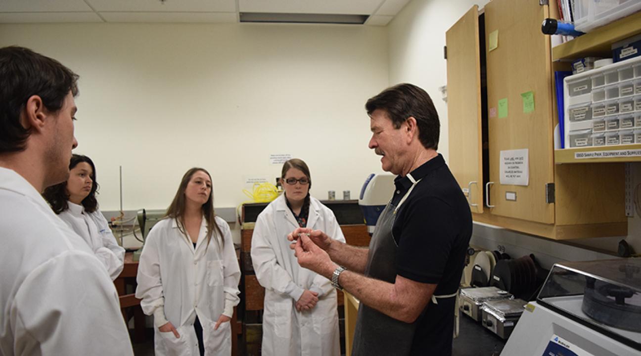 David Bero teaches a group of geology students how to make rocks thin enough for use under a microscope in a recent class