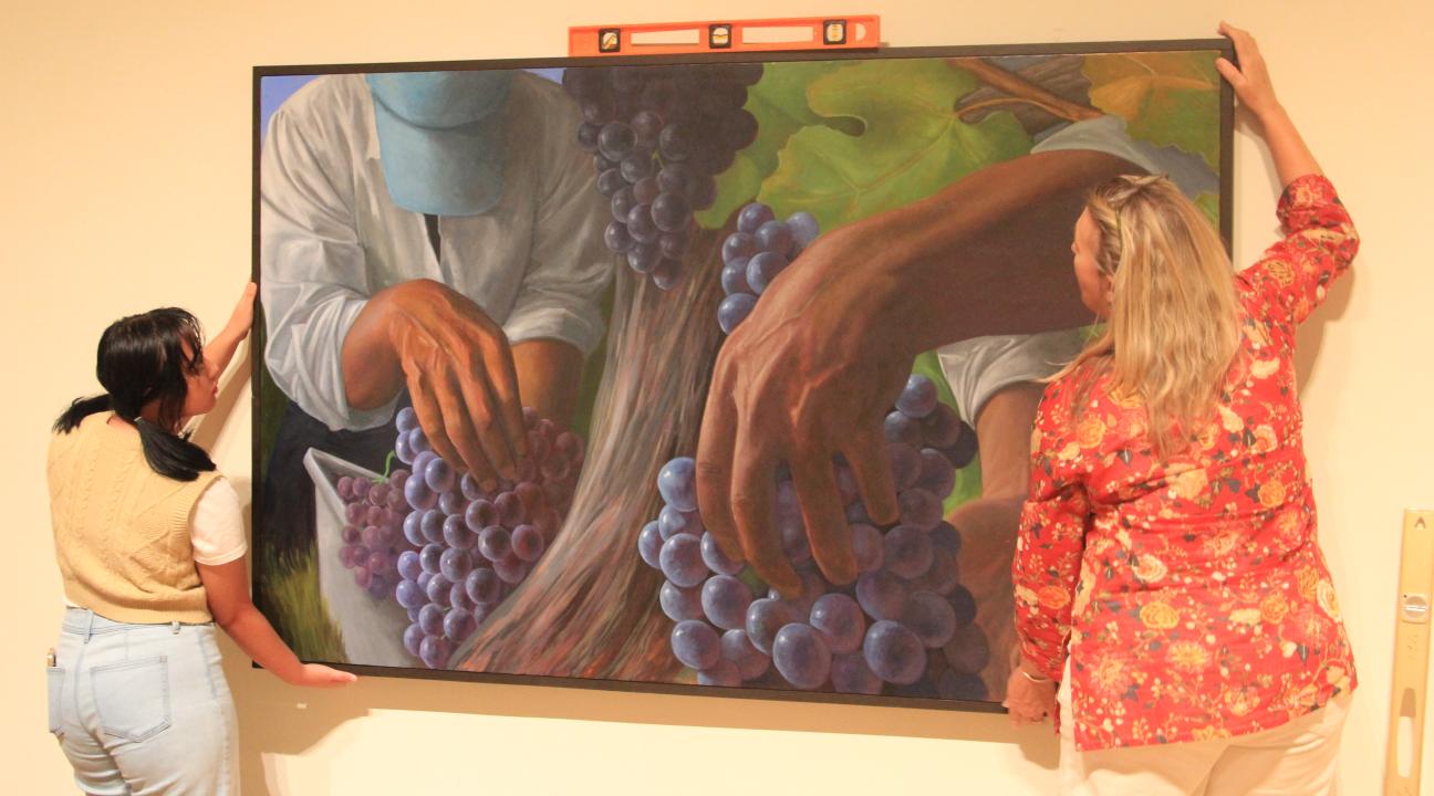 From left: Raiven Reyna, a third year art history major works with Gallery Exhibition Manager Carla Stone with exhibition installation. 