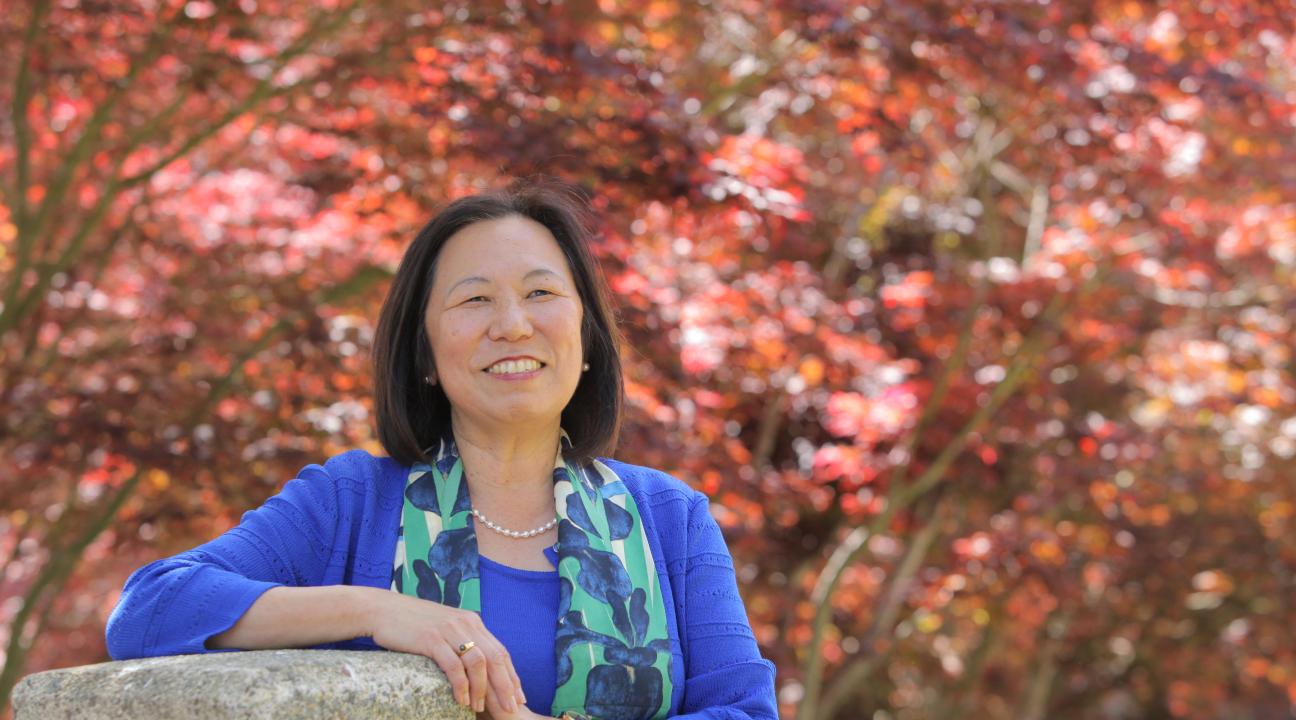 Image of Judy K. Sakaki in front of tree during the autumn.