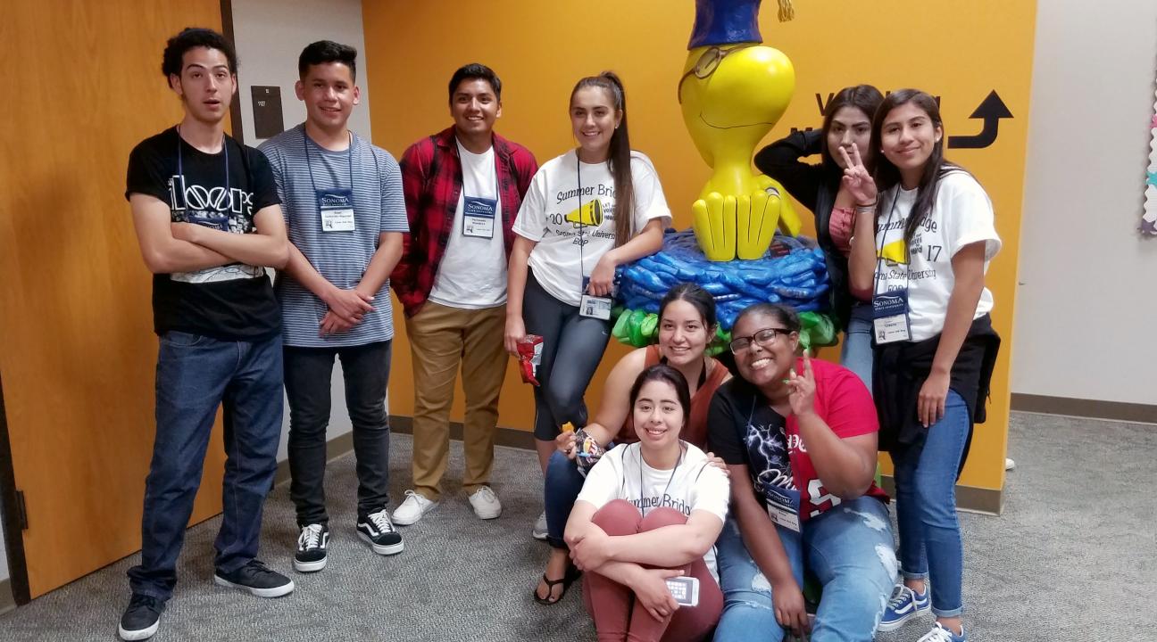 students pose with Woodstock sculpture in library