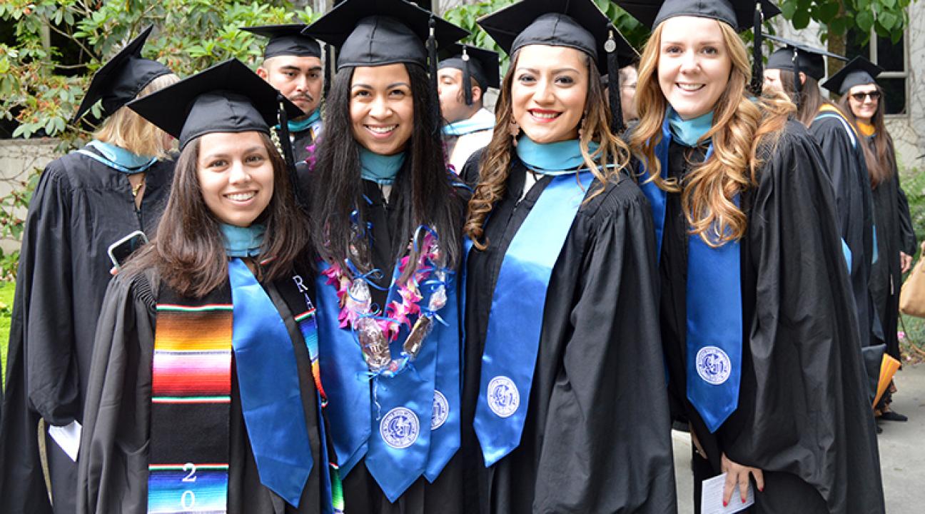 four students in regalia at commencement