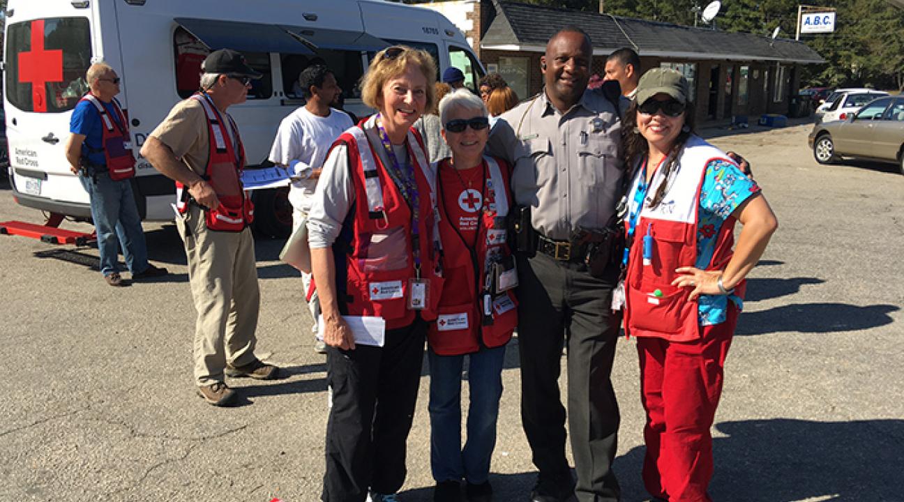  Ann Gang, Sally Bowers, a local police officer and Kathy De Bel help residents recover from Hurricane Matthew in North Carolina.