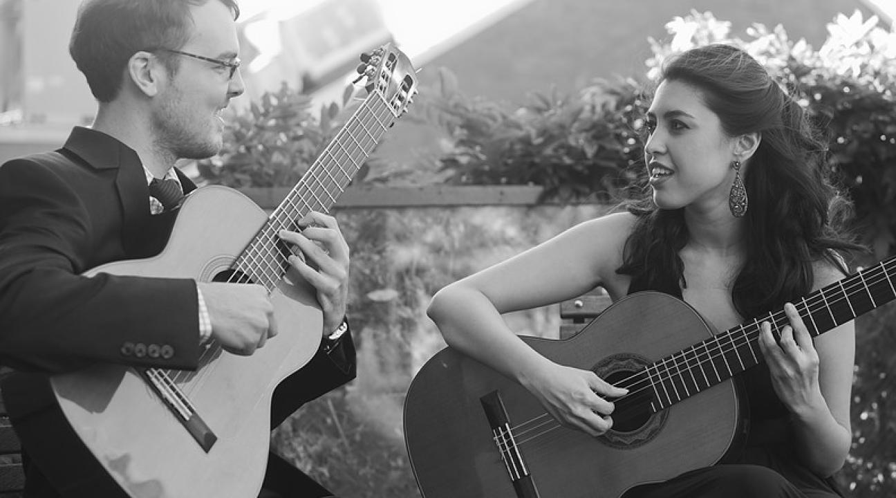 man and woman with acoustic guitars