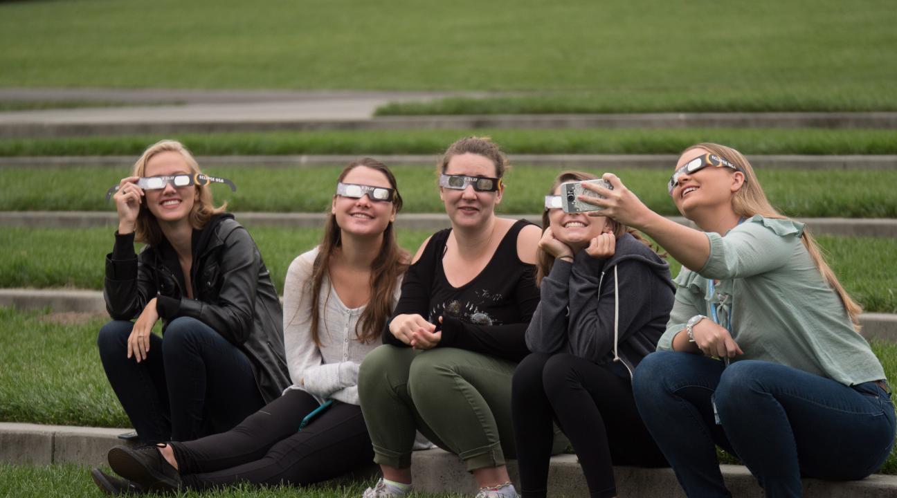 Students wear eclipse glasses at Convocation 2017 outside Weill Hall