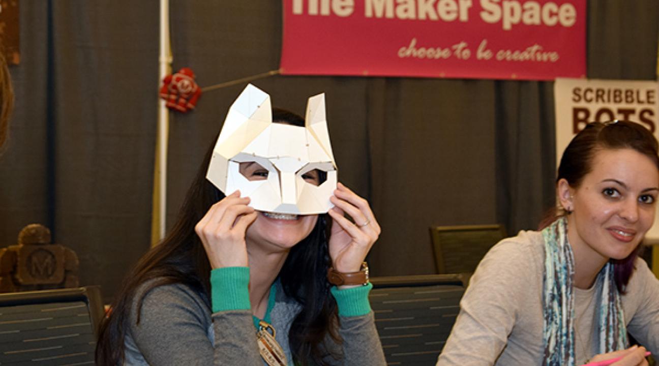 woman holding up paper fox mask