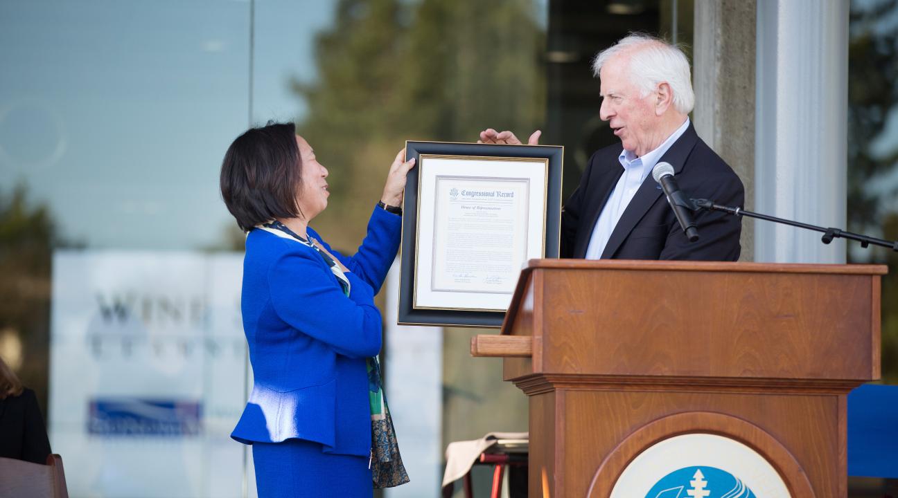 Rep. Mike Thompson hands President Judy K. Sakaki a copy of a Congressional Resolution honoring Sonoma State for the opening of the WSLC.