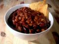a bowl of chili with two tortilla chips to the side.