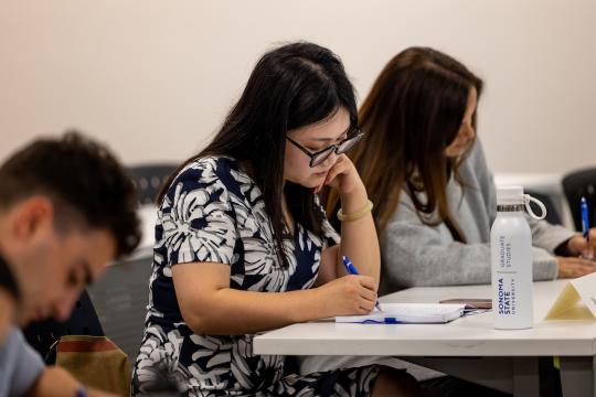 Student seated at desk, taking notes