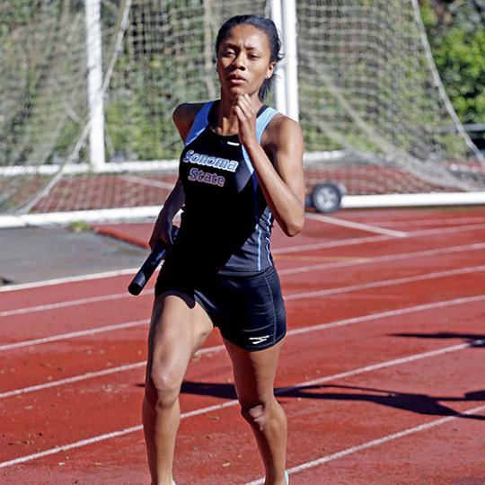 Angelique Lopez running with the baton at a track meet