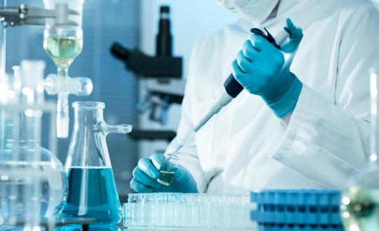 chemist injecting blue liquid into container