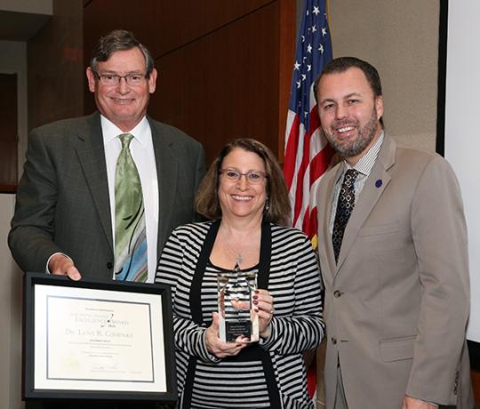CSU Chancellor Timothy White and Chair of the Board of Trustees, Lou Monville present SSU physics and astronomy professor Lynn Cominsky with the Wang Family Excellence Award