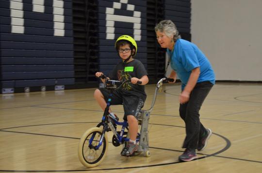 elaine mchugh helping a child ride a bike