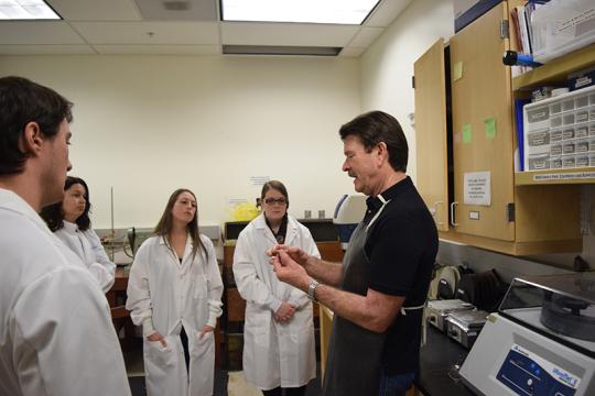 David Bero teaches a group of geology students how to make rocks thin enough for use under a microscope in a recent class