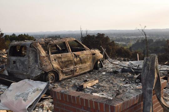 A destroyed car looks out over Santa Rosa to the west on Alturia Drive near the boulders at Fountaingrove, where hundreds of homes were lost in the Oct. 9 firestorm. // Photo by Paul Gullixson