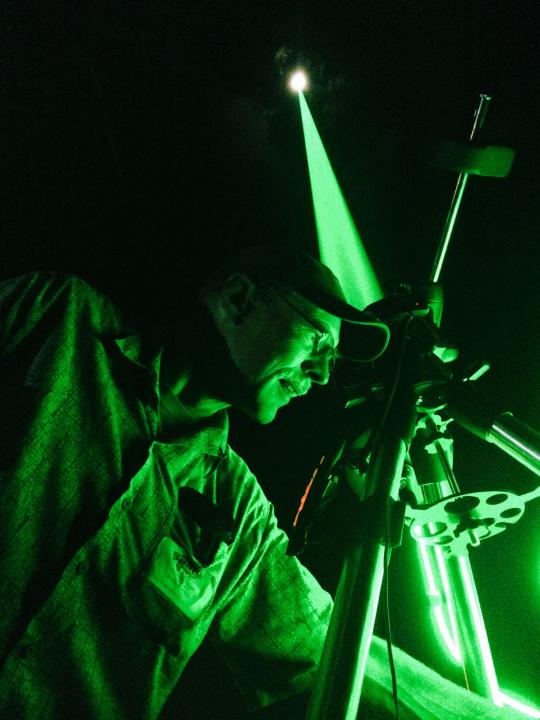 Green laser being shot at the moon