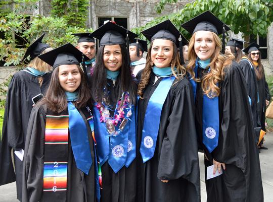 four students in regalia at commencement