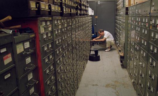 Still from Vanessa Gould's documentary film "Obit." (2016). Journalist looking through cabinets