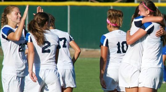 women's soccer celebrating goal