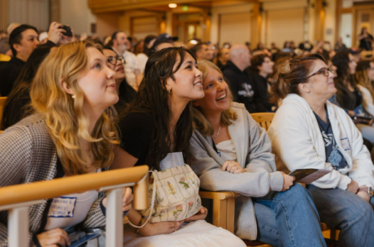 A group of people watching a presentation on stage
